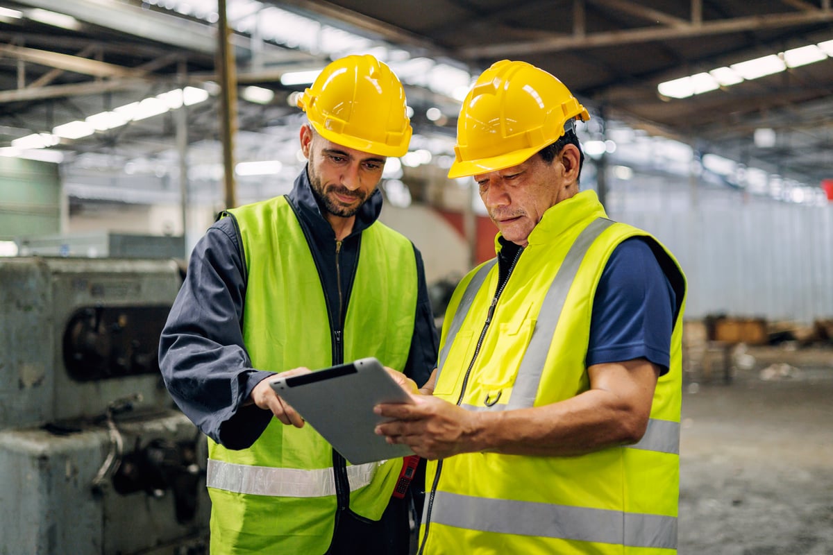 Engineers reviewing plans on tablet in factory